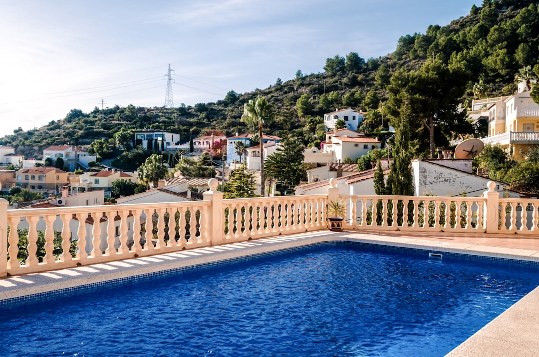 Swimming pool maintenance technician cleaning and checking pool equipment during summer in Spain