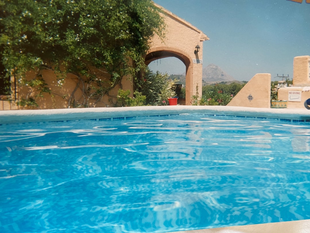 A technician cleaning and skimming a swimming pool on a sunny Costa del Sol terrace
