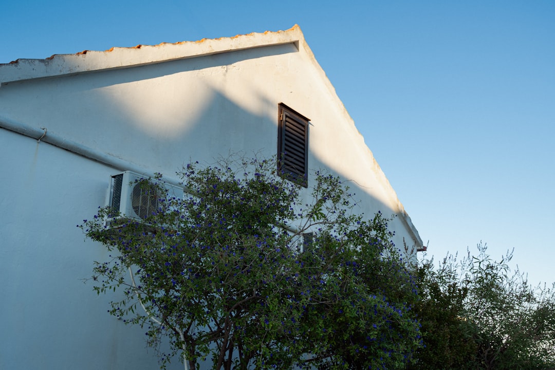 Air conditioning outdoor condenser unit mounted on a white wall in Costa del Sol, Spain, requiring regular annual servic